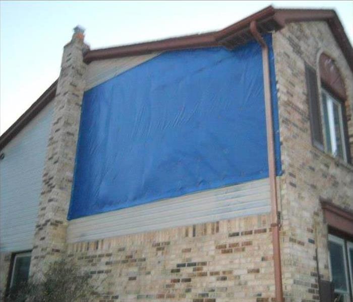 home with tarp on it after storm damage 