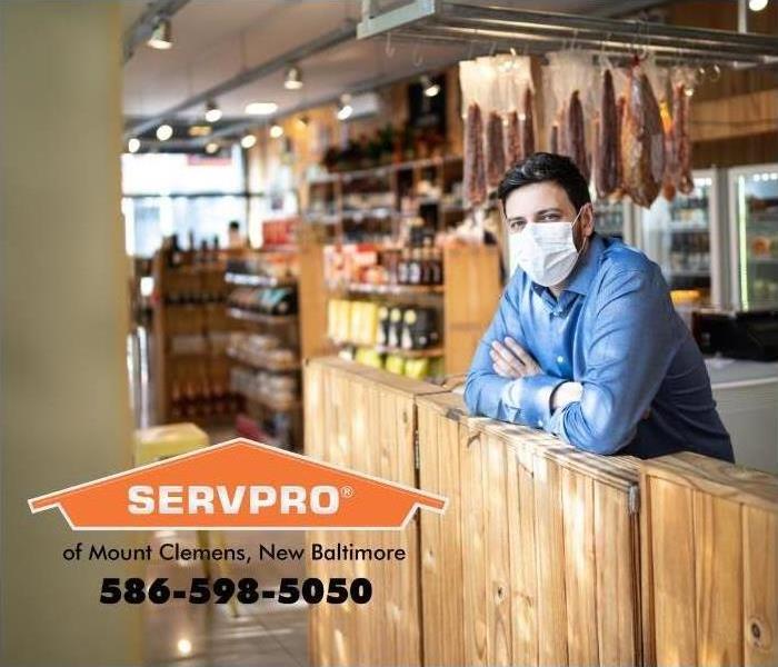 man in mask leaning on counter at deli 