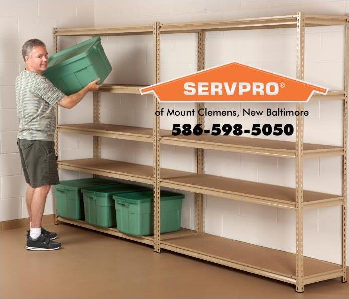 A man is shown placing green plastic bins on a new storage shelving unit in his basement.