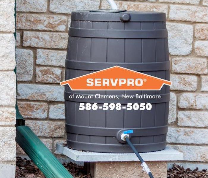 Rainwater is flowing from a downspout into a rain barrel from a downspout. 