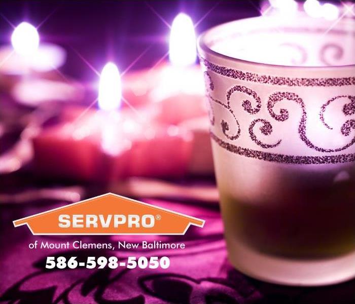 Many candles are lit and are sitting on top of a deep wine-colored tablecloth.